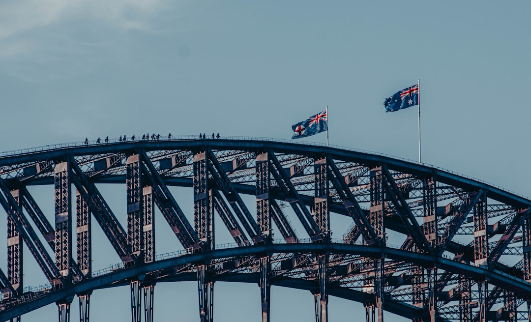 crypto licensing australia - red and white flag on black steel bridge under blue sky during daytime