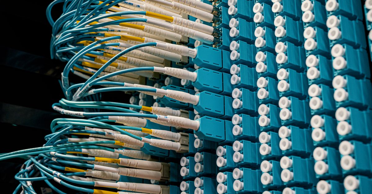 green bond market - Detailed view of fiber optic patch cables connecting to a blue patch panel in a data center.