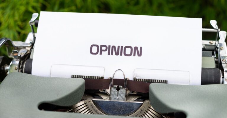 Close-up of a typewriter with paper showing the word 'Opinion' outdoors.