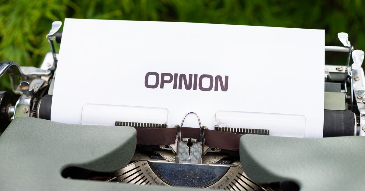 Close-up of a typewriter with paper showing the word 'Opinion' outdoors.