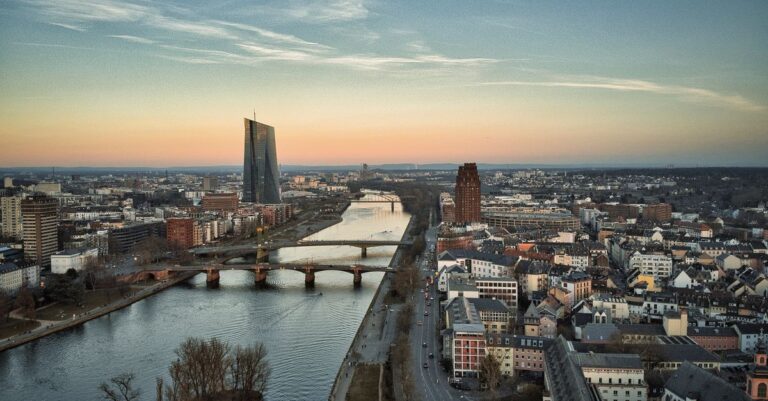 binance mica fight - A stunning aerial view of Frankfurt am Main featuring the iconic ECB Tower and the Main River at sunset.