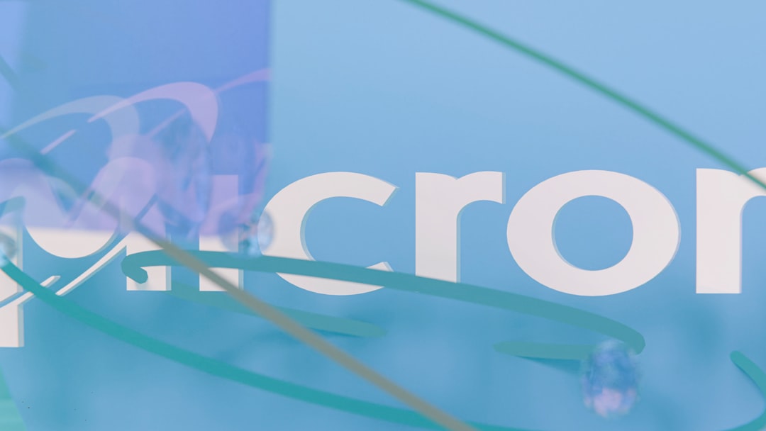 micron stock - Partial micron logo on light blue background with abstract swirls.