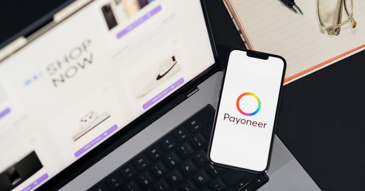 nuvei payoneer acquisition - Mobile phone with Payoneer app on screen next to laptop displaying online shopping site.