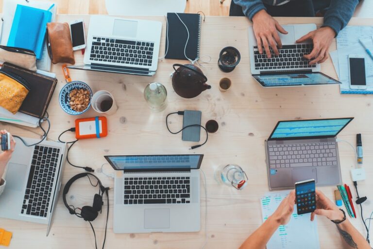 remote work startup - people sitting down near table with assorted laptop computers