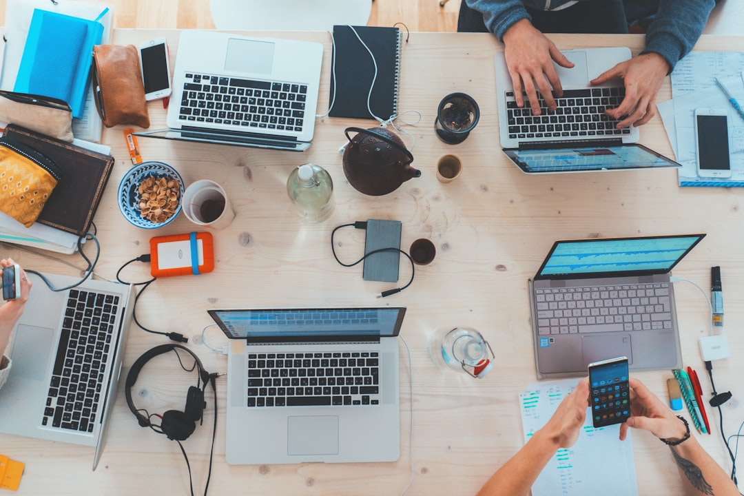 remote work startup - people sitting down near table with assorted laptop computers