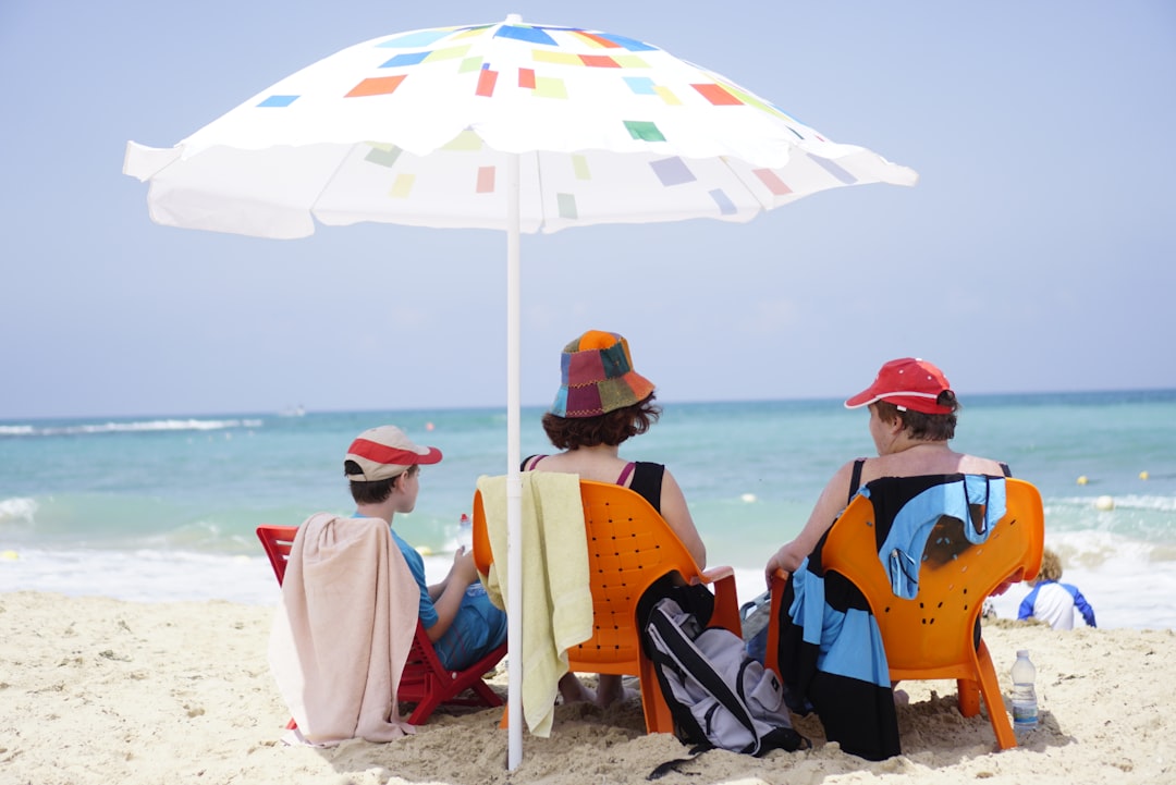 sunscreen fda approved - three people sitting under an umbrella on the beach