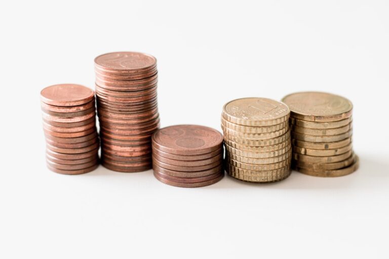 growth value stocks - stacked round gold-colored coins on white surface