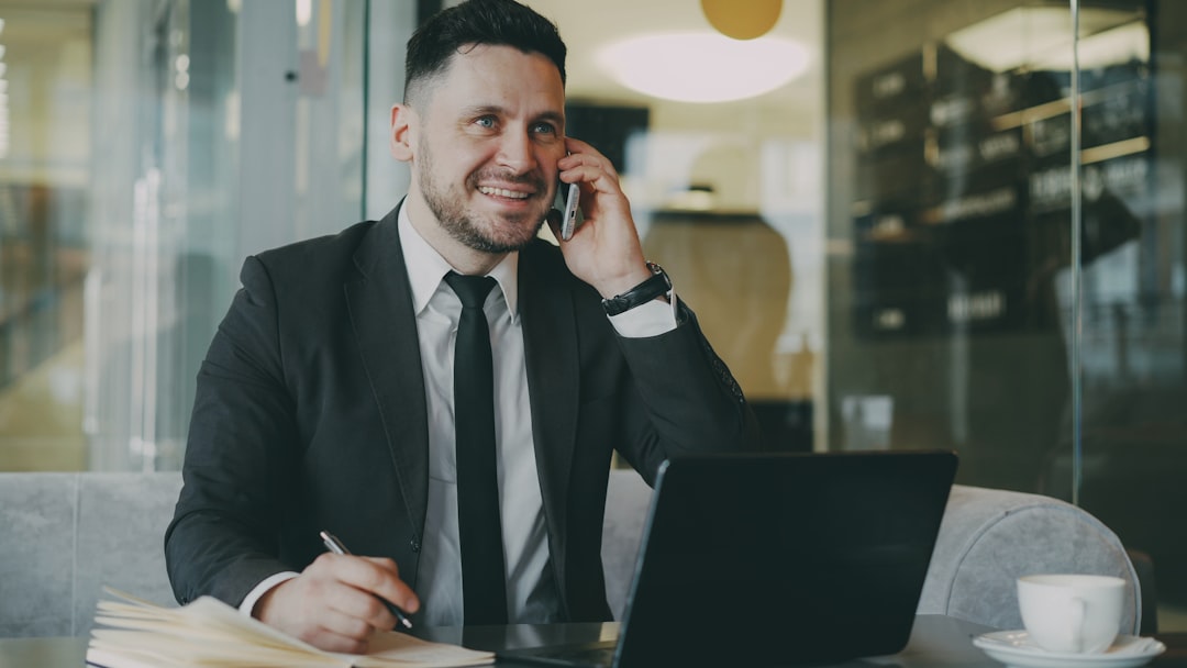 small business efficiency - Man in suit talking on phone at laptop