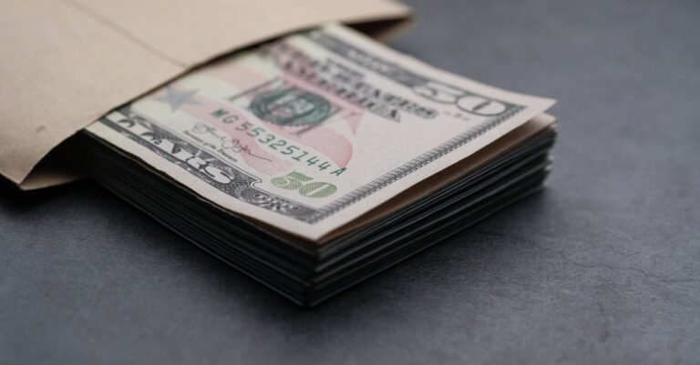 great wealth transfer - Close-up of US fifty dollar bills partially enclosed in a brown envelope, symbolizing finances.