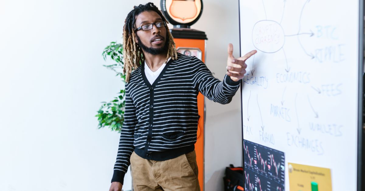 agentic AI finance - Man explaining cryptocurrency concepts on a whiteboard in a modern office setting.