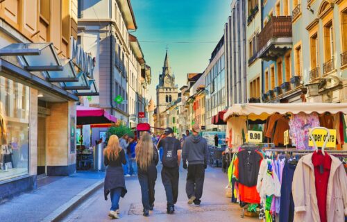 ai in banking - People walk down a sunny european street with shops.