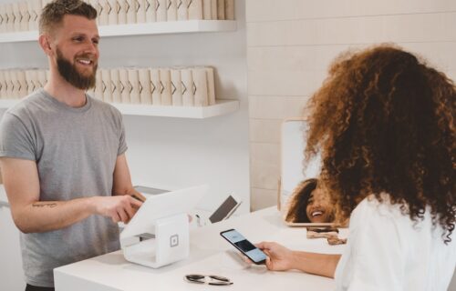 ai customer experience - man in grey crew-neck t-shirt smiling to woman on counter