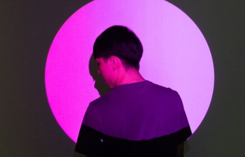 monzo anthropic blomfield - A person stands in front of a bright pink circular light, creating a striking silhouette effect.