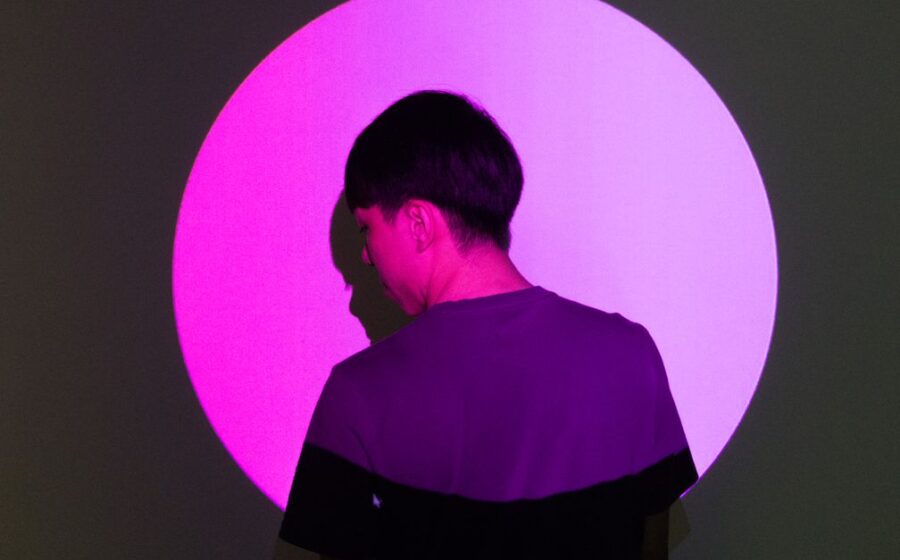 monzo anthropic blomfield - A person stands in front of a bright pink circular light, creating a striking silhouette effect.