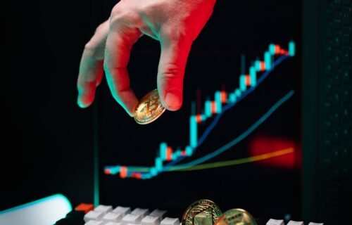 ai in banking - A hand reaching for a coin on a computer keyboard