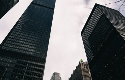 bank stock earnings - Low angle view of modern skyscrapers against a cloudy sky in a city.