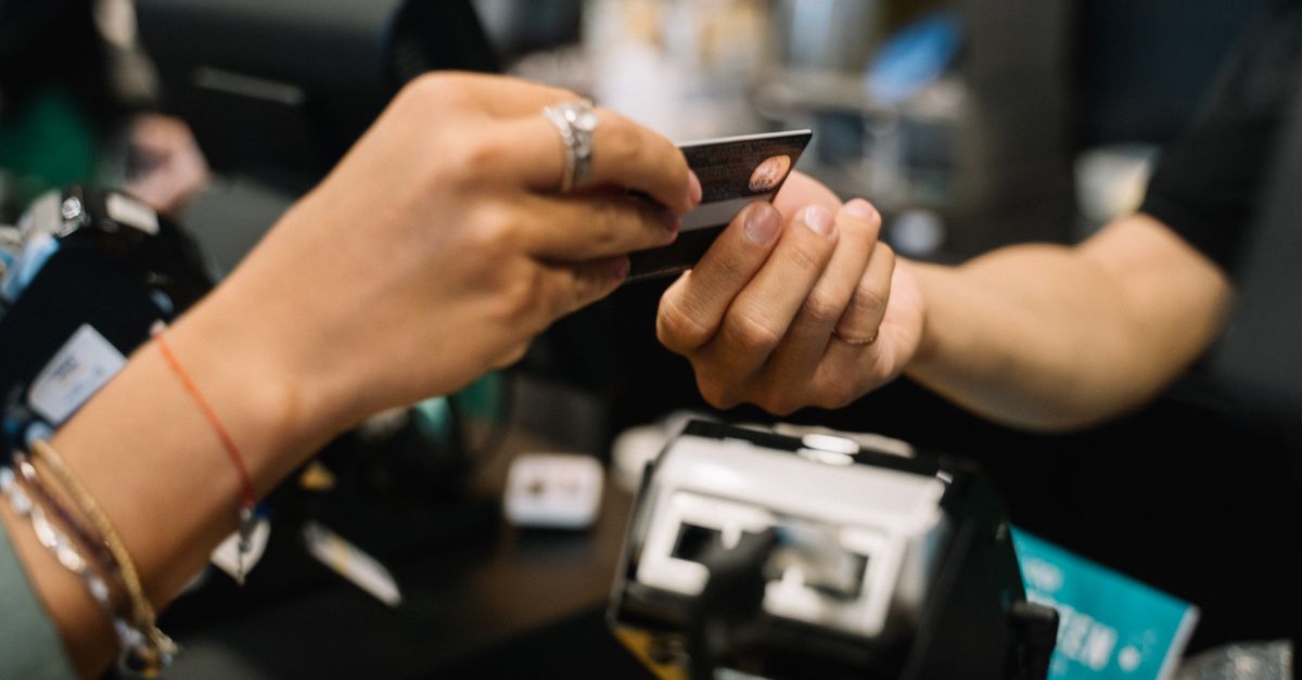 bnpl users financial need - Close-up of hands completing a payment transaction at a retail checkout using a bank card.