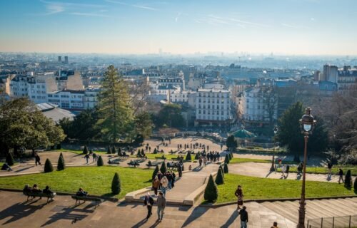 polymarket france ban - People walk down a hill overlooking the city.