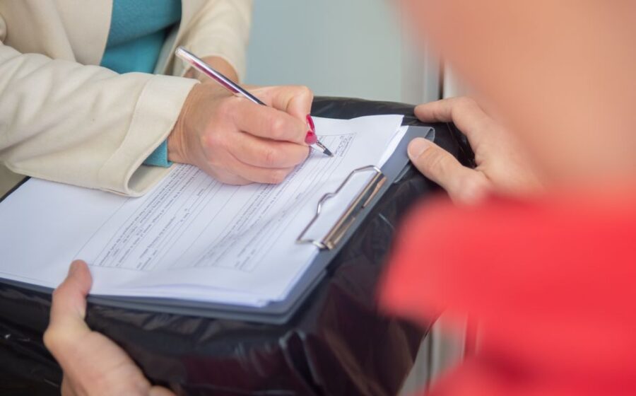 mica register bny mellon - Focused image of hands signing an important document on a clipboard, illustrating a business agree
