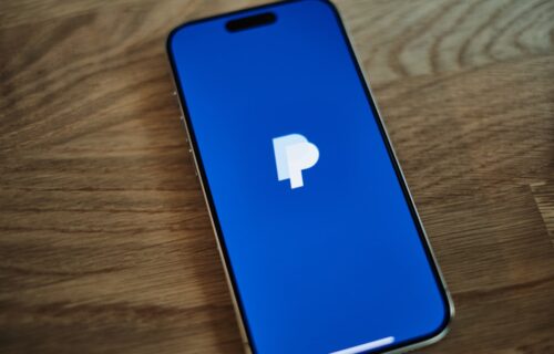 paypal earnings merger - A blue iPhone sitting on top of a wooden table