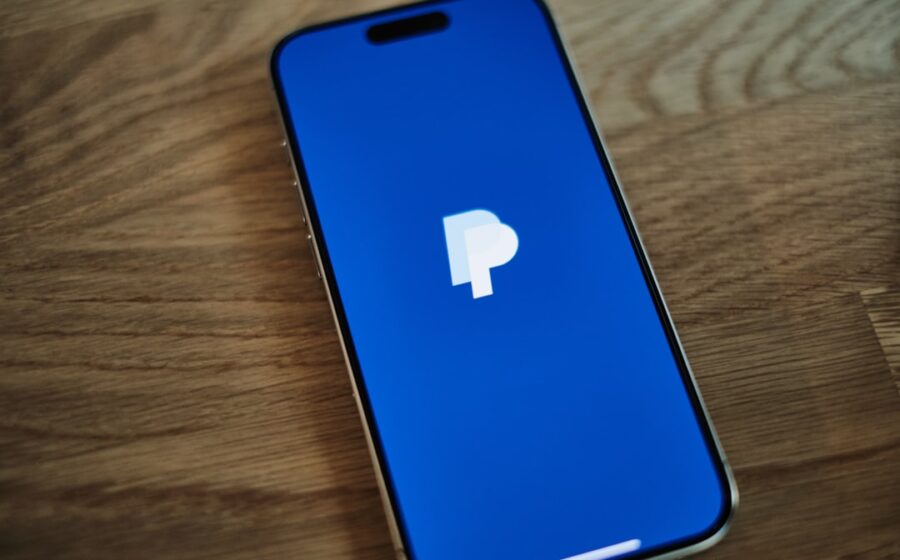 paypal earnings merger - A blue iPhone sitting on top of a wooden table