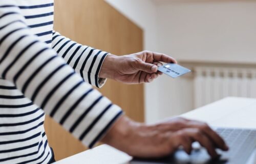 stripe ai billing - Person using a credit card for online shopping on a laptop indoors.