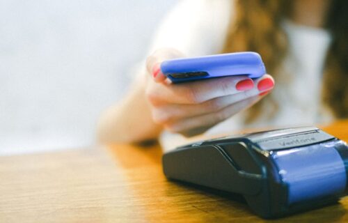 payment terminal tampering - Close-up of a woman making a contactless payment using a smartphone over a card reader