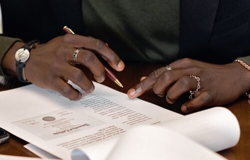 wise bank charter rejected - A business professional's hands signing a document at a desk, focusing on details.