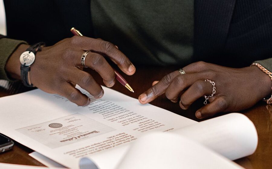 wise bank charter rejected - A business professional's hands signing a document at a desk, focusing on details.
