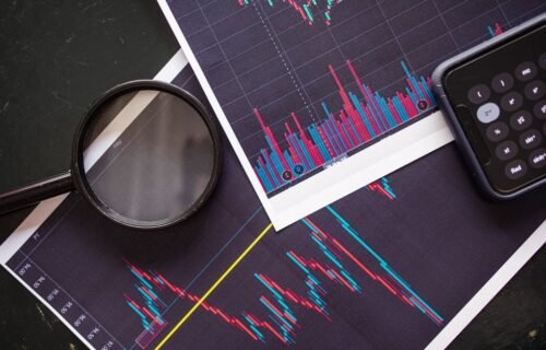 ai supercycle - Stock market charts analyzed with a magnifying glass and calculator for financial research.