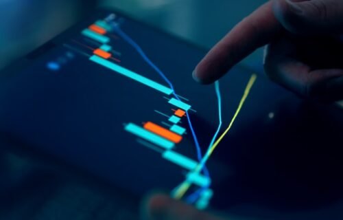 invest in ai - Fingers interacting with a stock market graph on a tablet.