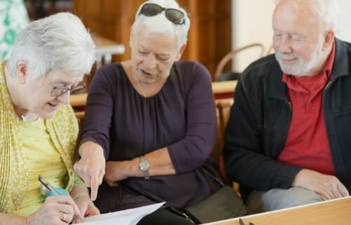 social security funding - Three older adults are looking at a paper.