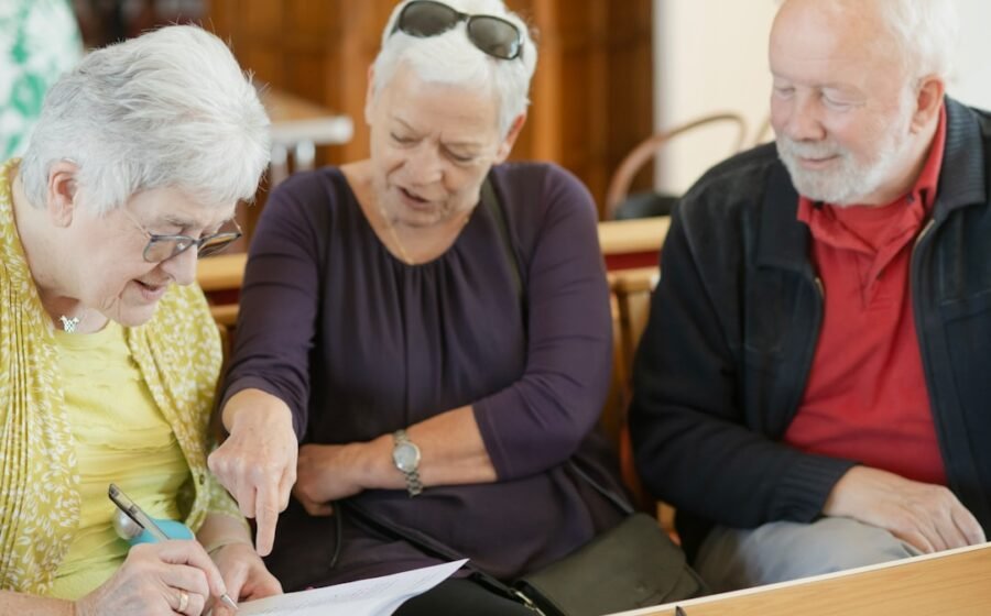 social security funding - Three older adults are looking at a paper.