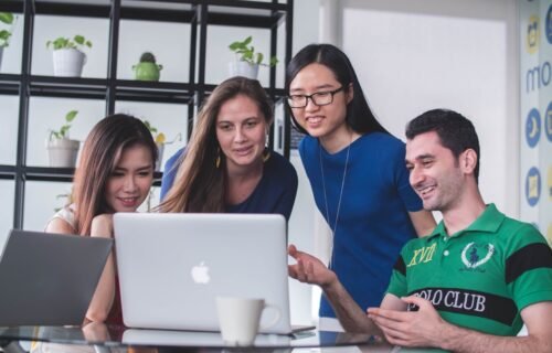 fintech tools for startups - four people watching on white MacBook on top of glass-top table