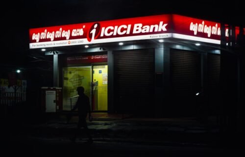 banks add branches - Icici bank building illuminated at night, person walking nearby
