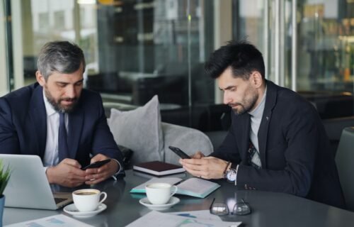 ai banking platform - two men sitting at a table looking at their phones