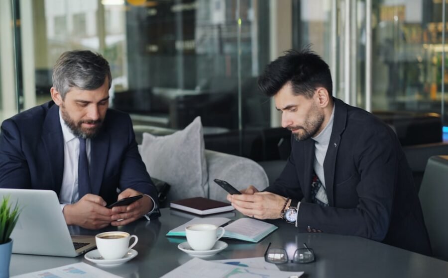 ai banking platform - two men sitting at a table looking at their phones