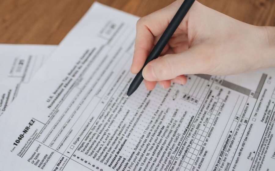 fincen smuggling data - Close-up of a hand writing on tax documents with a black pen.