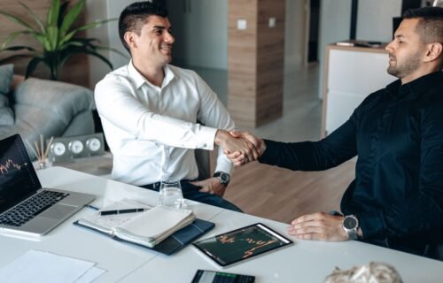 autonomous finance startup - Two businessmen shaking hands in an office, symbolizing a successful business agreement.
