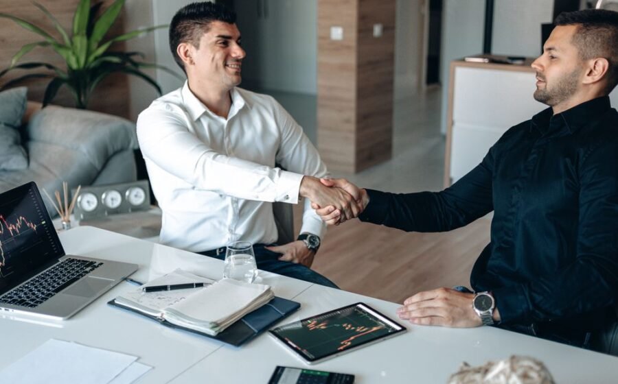 autonomous finance startup - Two businessmen shaking hands in an office, symbolizing a successful business agreement.