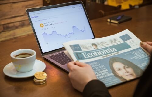 a person reading a newspaper next to a cup of coffee