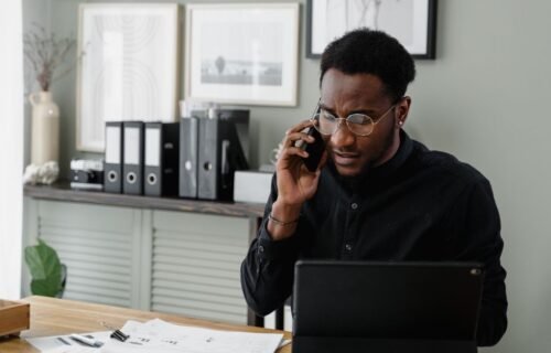 marqeta deal size - Professional man working at his desk on a call, managing documents and using a tablet.