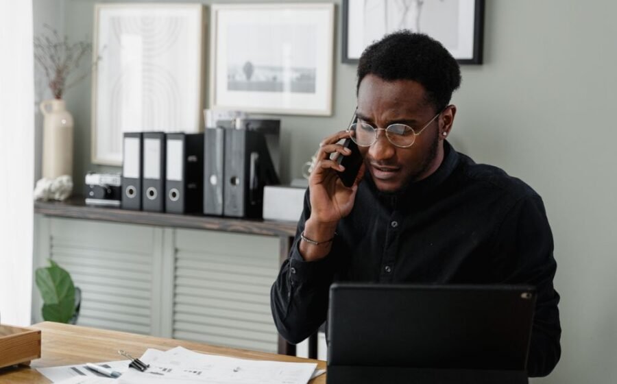 marqeta deal size - Professional man working at his desk on a call, managing documents and using a tablet.