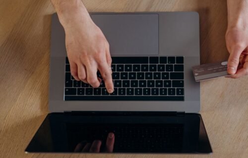monzo business accounts - Top view of hands using a credit card and laptop for online transactions on a wooden surface.