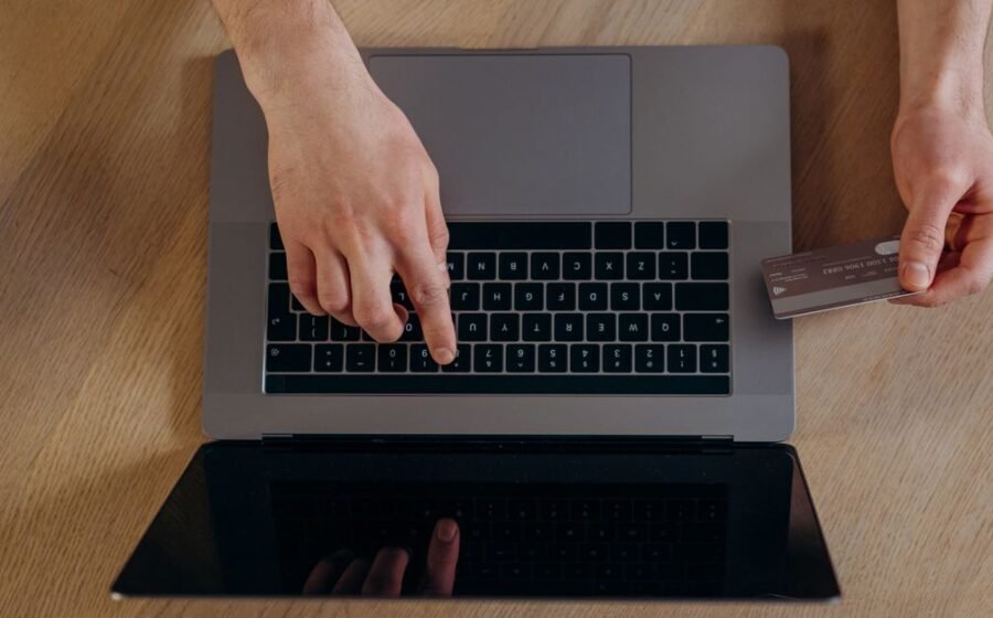 monzo business accounts - Top view of hands using a credit card and laptop for online transactions on a wooden surface.