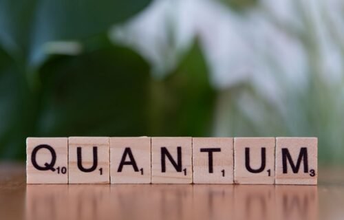 quantum computing growth - Creative depiction of 'quantum' using wooden letter blocks on a blurred natural background.