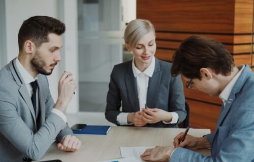 Business people signing a contract at a table.