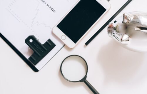 wealthtech wealth management technology - A flat lay of financial documents with a smartphone, magnifying glass, and piggy ba