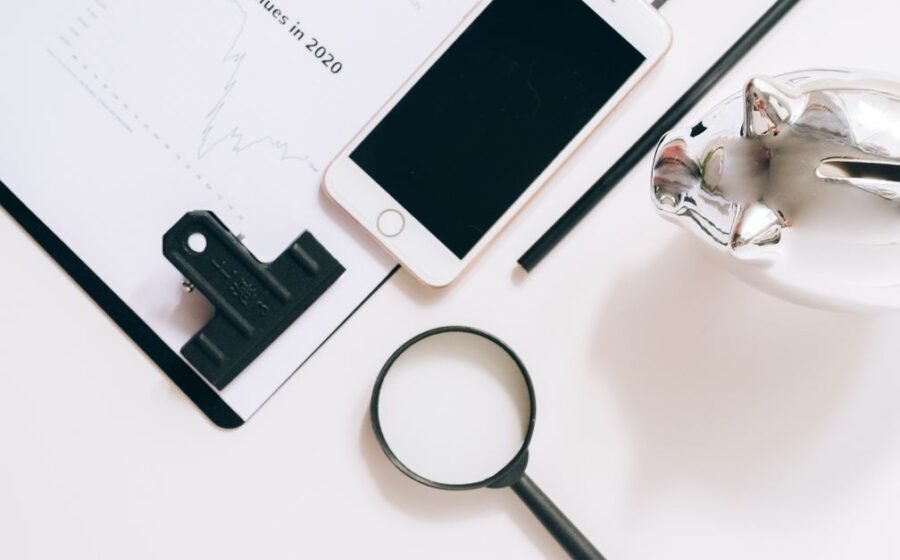 wealthtech wealth management technology - A flat lay of financial documents with a smartphone, magnifying glass, and piggy ba