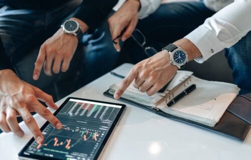 wealthtech funding drops - Two businessmen discussing financial data on a tablet during a meeting.
